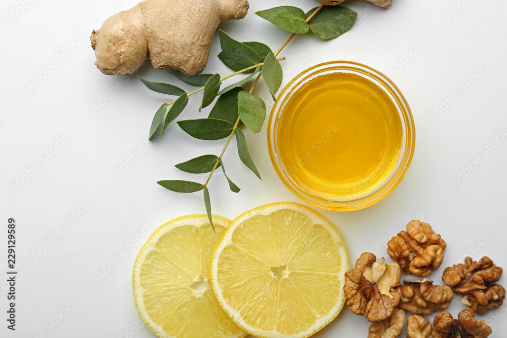 Honey, nuts, ginger and sliced lemon on light background