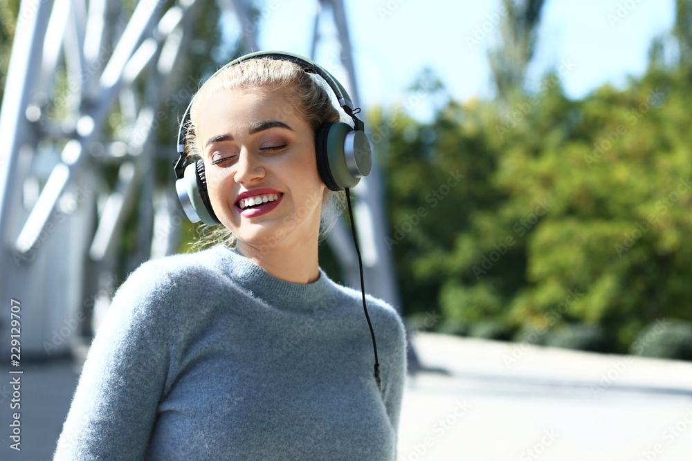 Beautiful young woman listening to music outdoors