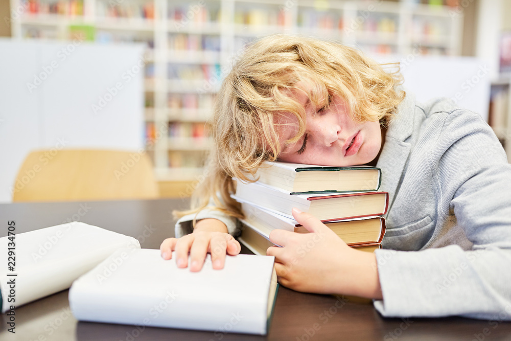 Junge schläft erschöpft in der Bibliothek