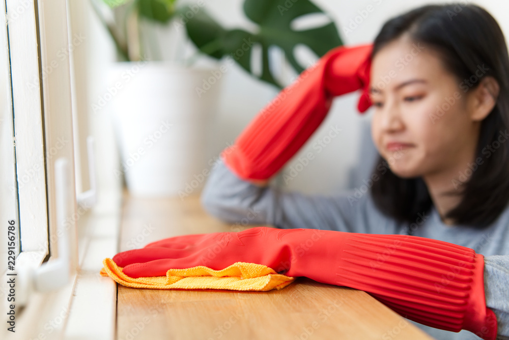 美丽幸福的年轻亚洲女性在用抹布擦拭地板上的灰尘时感到无聊和疲惫