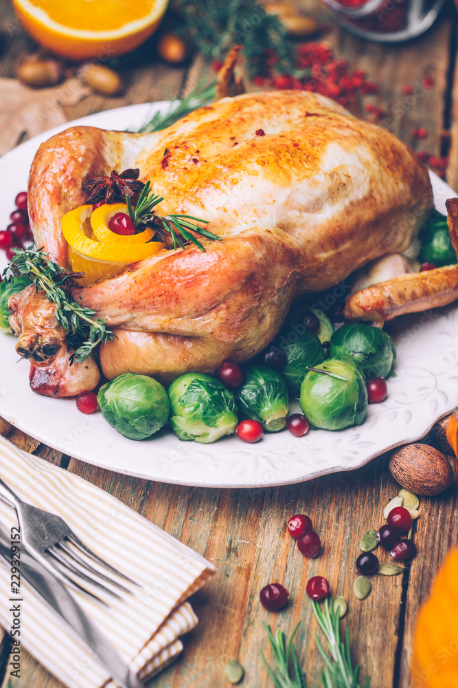 Thanksgiving roasted chicken with Brussels sprouts and spices on a rustic wooden table. Thanksgiving