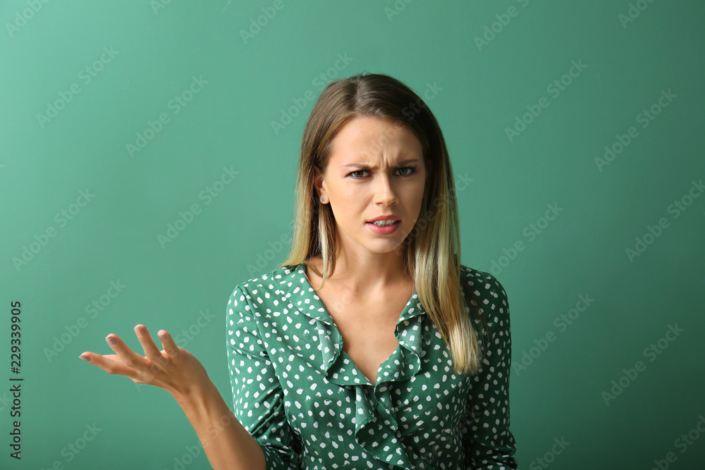 Indignant young woman on color background