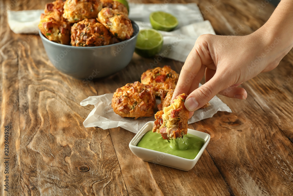 Woman eating sausage balls with tasty sauce