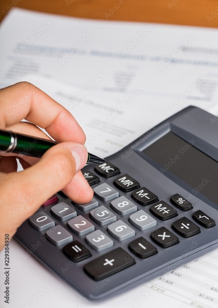 Close-up of a Businessman Using Calculator with Financial