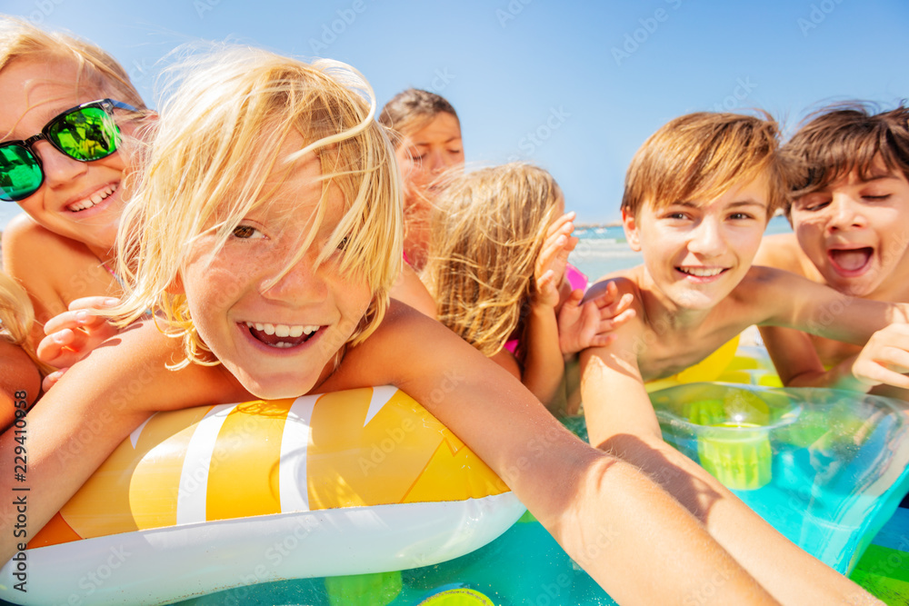 Cute boy taking selfie with friends on the beach