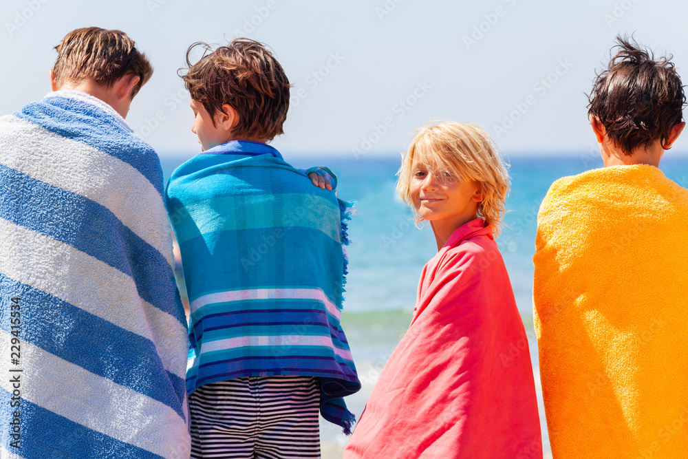 Boy in beach towel after sea swimming with friends