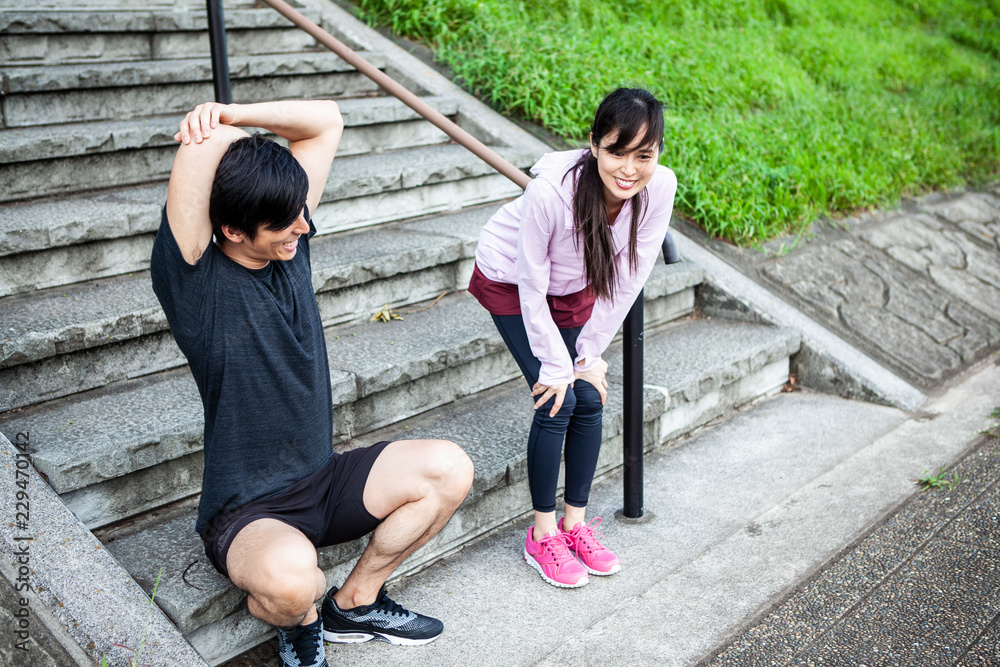 屈伸をしている女性。腕の筋肉をほぐす男性。