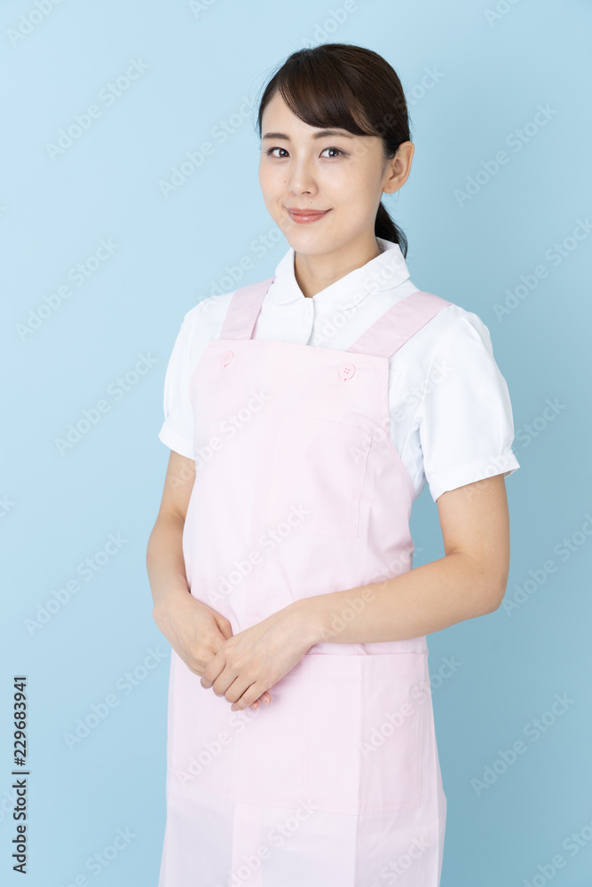 portrait of young asian nurse wearing apron on blue background