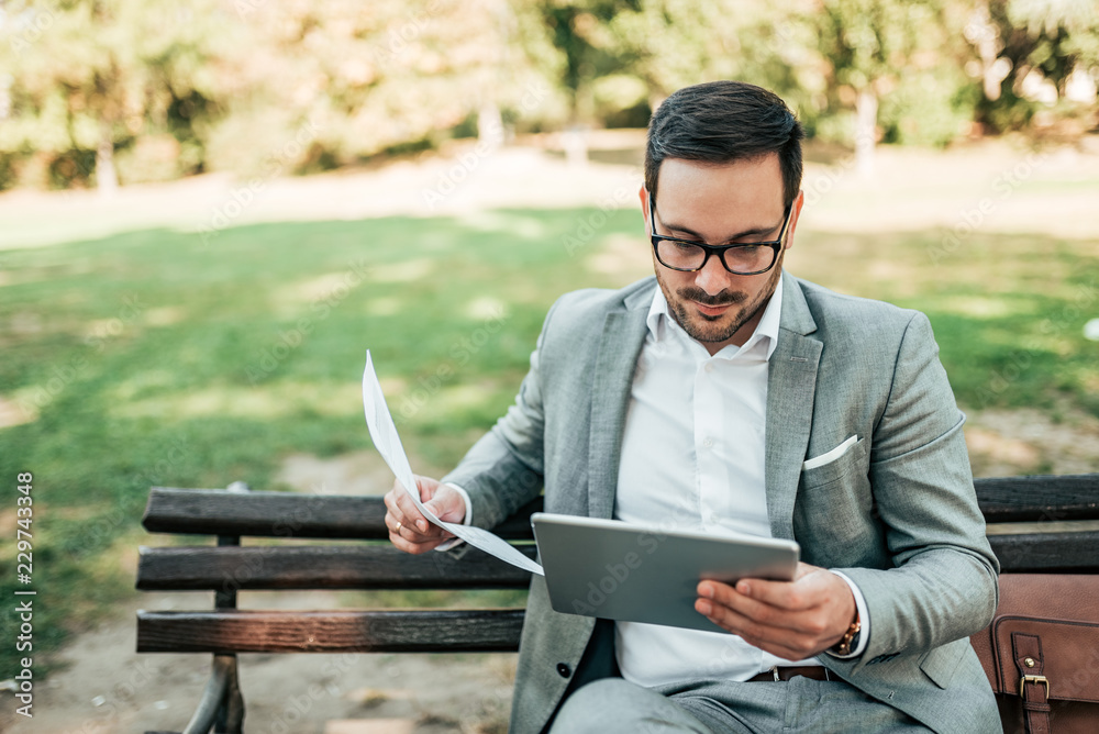 Handsome business man working in the park.