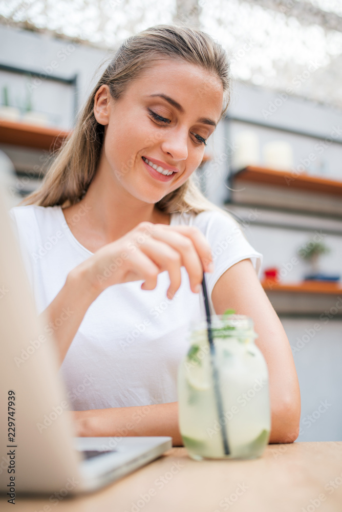 微笑的年轻女人在喝柠檬水。