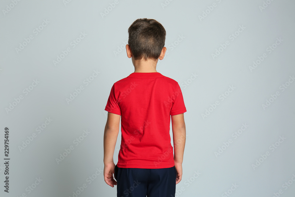 Little boy in t-shirt on grey background, back view