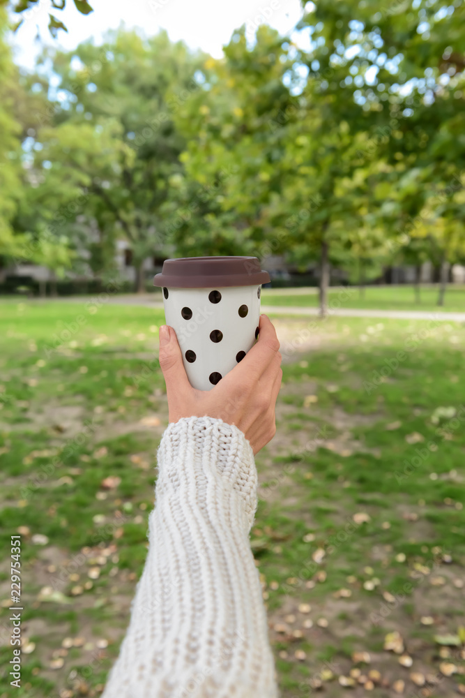 Woman holding coffee cup in park