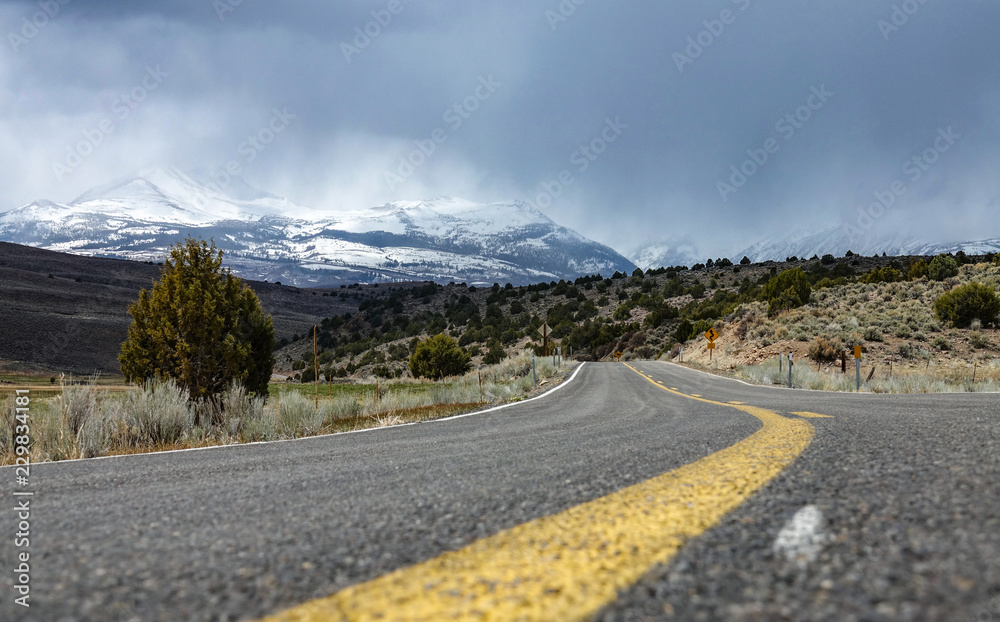 低角度：通往令人惊叹的雪山的空沥青路。