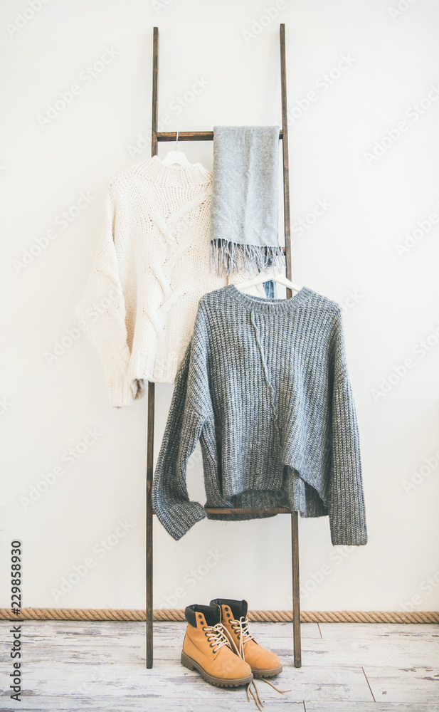 Fall or winter warm knitwear on hanger, white wall background. Fashionable female winter clothing. W