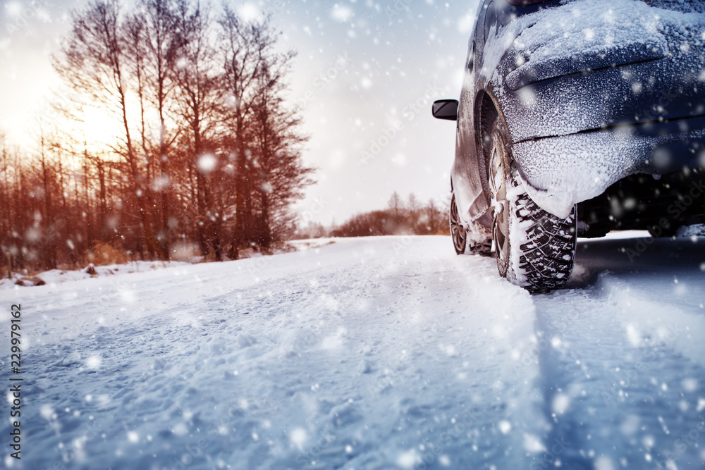 冬季道路上的汽车轮胎被雪覆盖。早上下雪时车辆在雪地上行驶