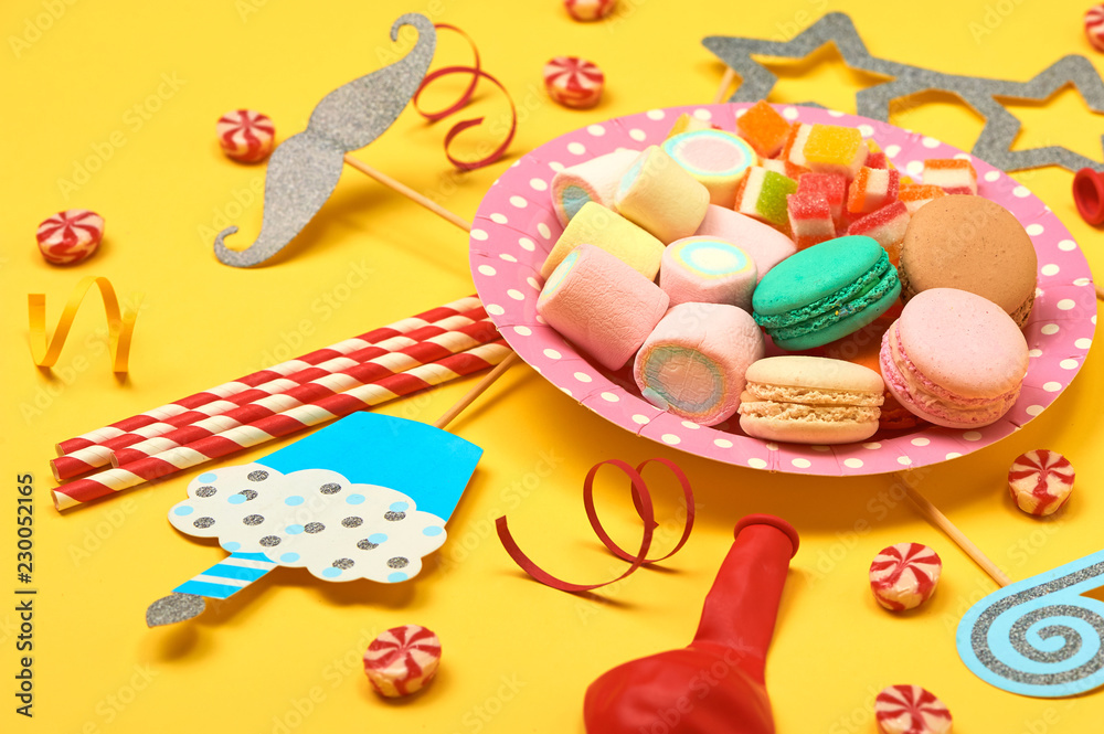 Colored party, sweets and confetti on yellow background top view mockup