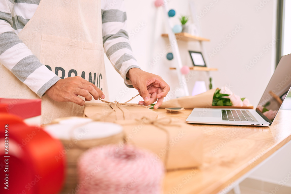 亚洲男子在礼品店工作时进行包装采购。