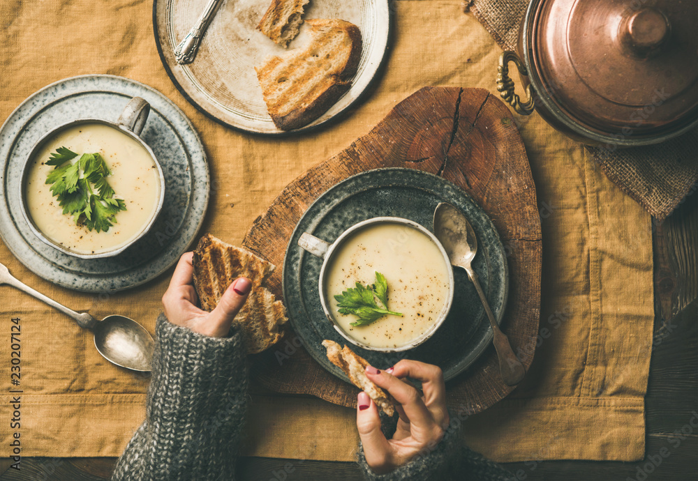 Autumn, Winter home dinner. Flat-lay of Fall warming celery cream soup and female hands with grilled