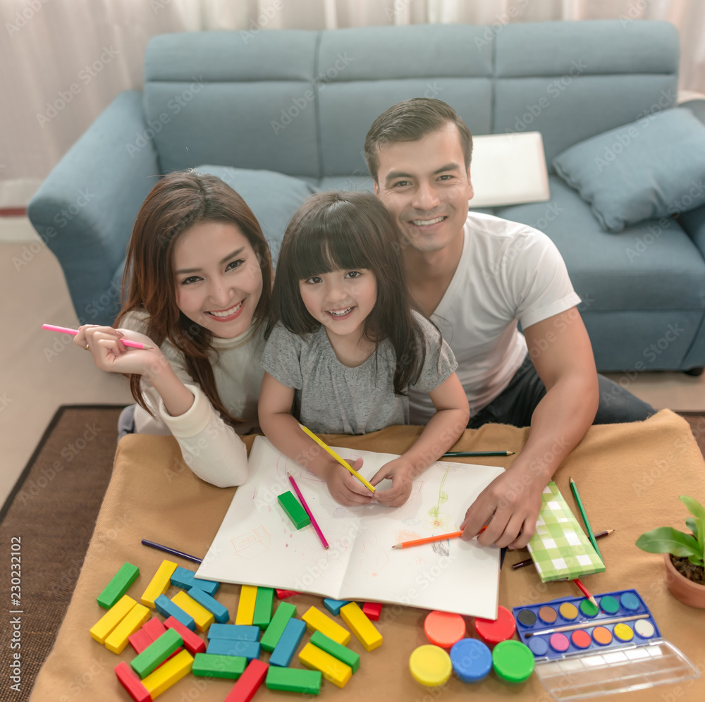 Portrait of happy family daughter and parent drawing and reading together