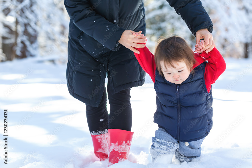 蹒跚学步的男孩和妈妈在雪地里玩耍