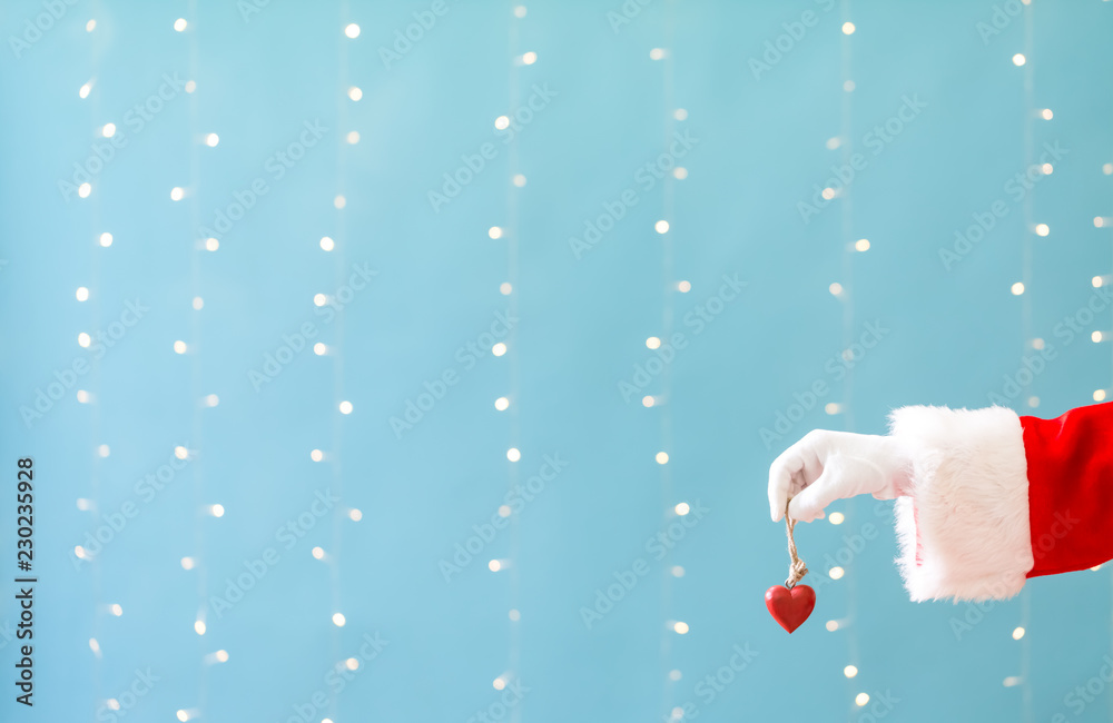 Santa holding a Christmas heart on a shiny light blue background