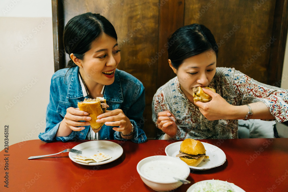 饥饿的女士们快乐地吃着汉堡