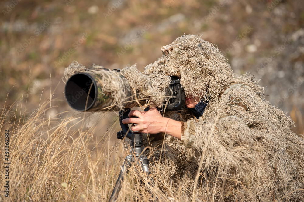 Wildlife photographer in the ghillie suit working