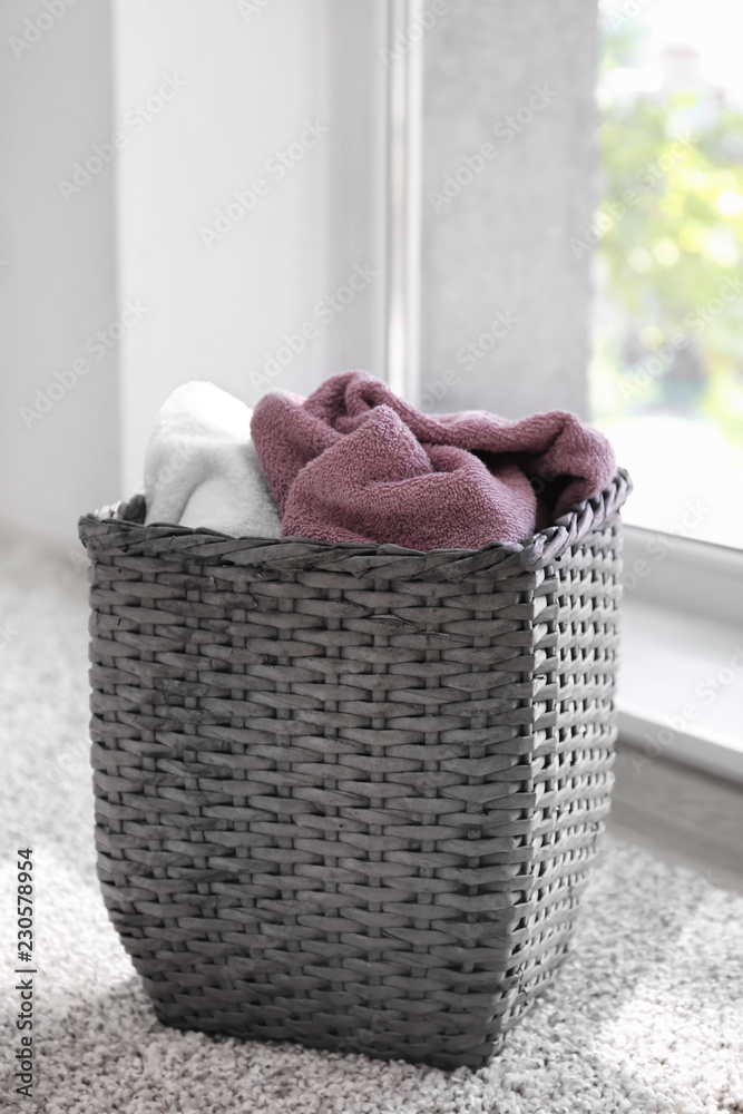 Laundry basket with dirty towels on floor near window