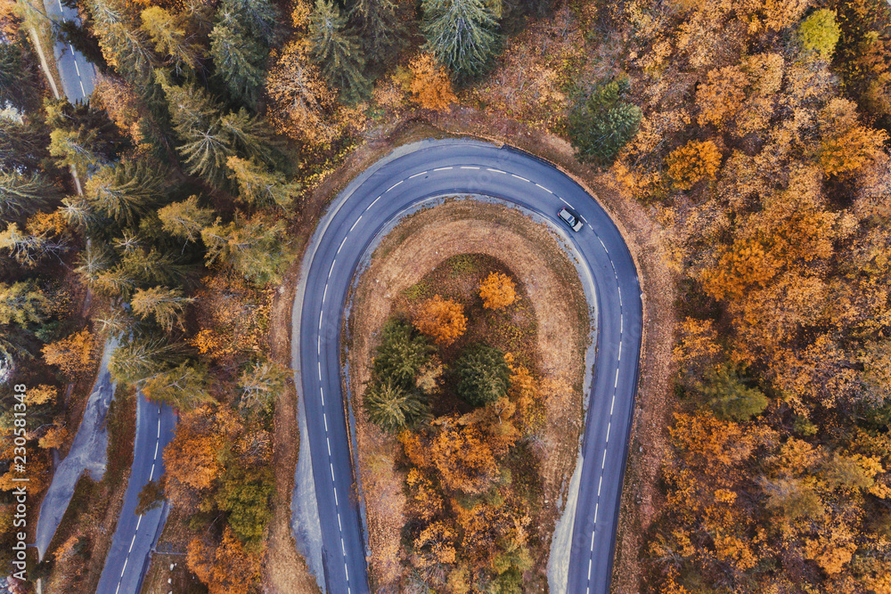 秋天森林里的美丽道路。秋天的空中景观，汽车在山上行驶的俯视图