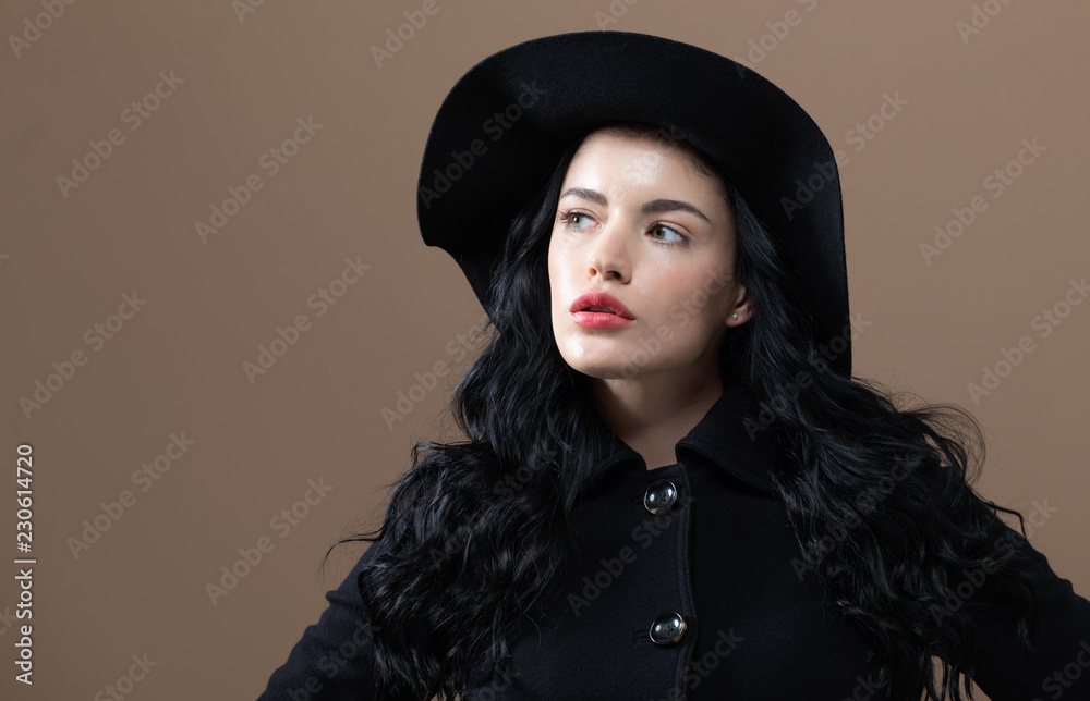 Beautiful young woman in a fashionable coat on a brown background