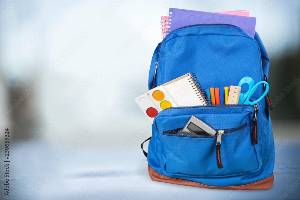 Colorful school supplies in backpack on wooden