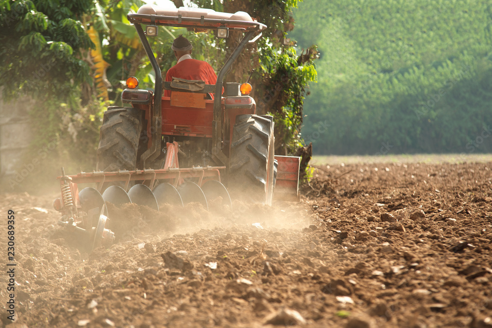 Tractor cultivating field at spring,Tillage is the agricultural preparation of soil by mechanical ag