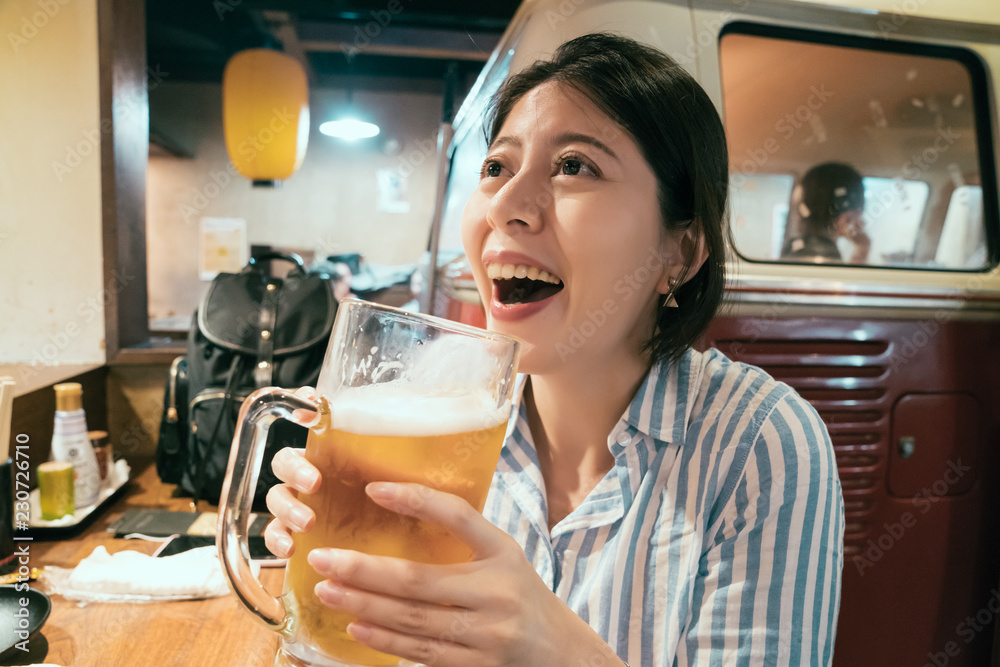 年轻女子晚上在日本酒吧喝酒。