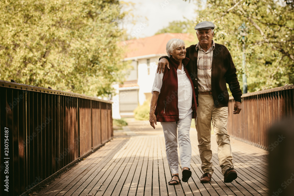 Happy elderly couple walking through a park