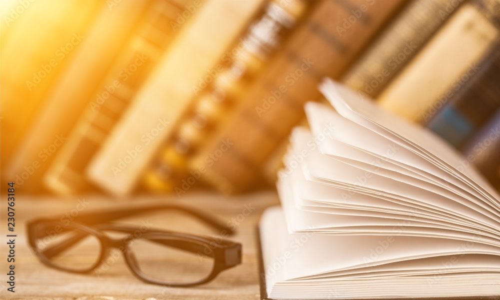 Open book and glasses on wooden table