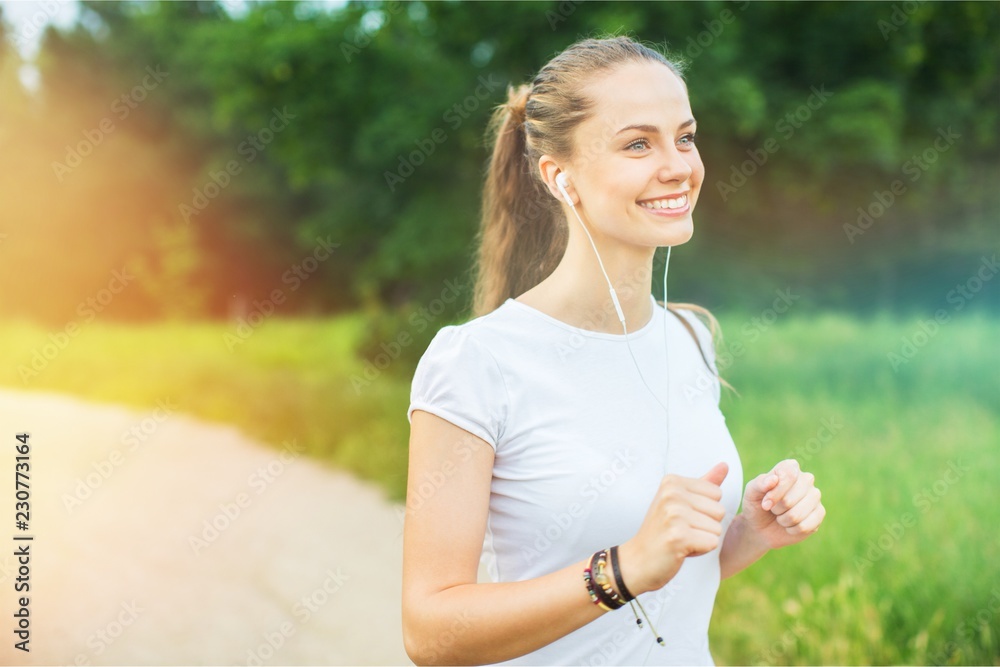 年轻漂亮女人在公园里跑步听音乐