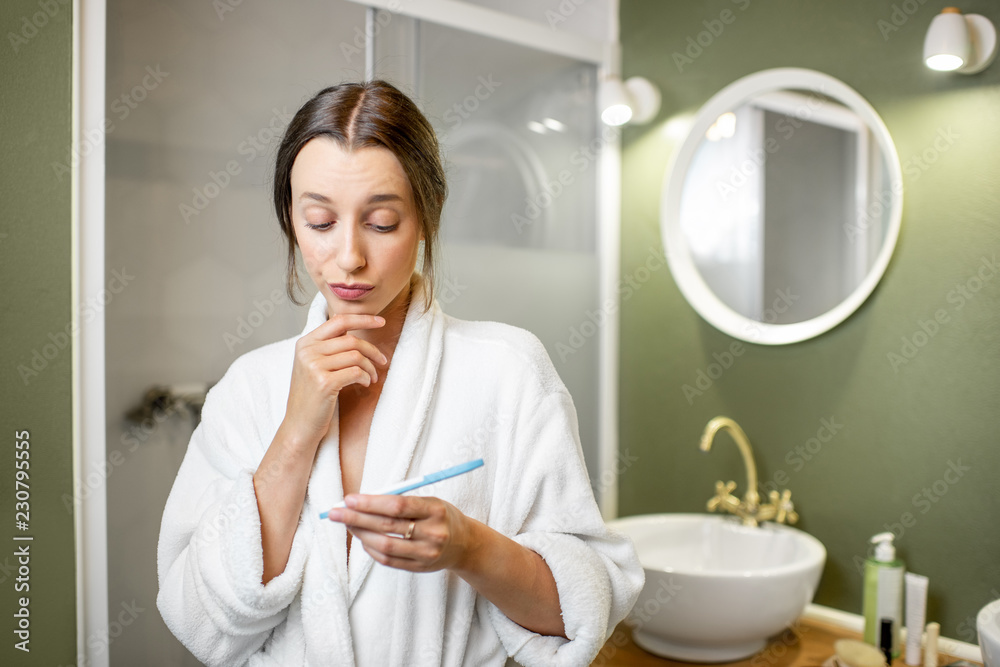 穿着浴袍等待结果的悲伤而担忧的女人在浴缸里看着验孕棒