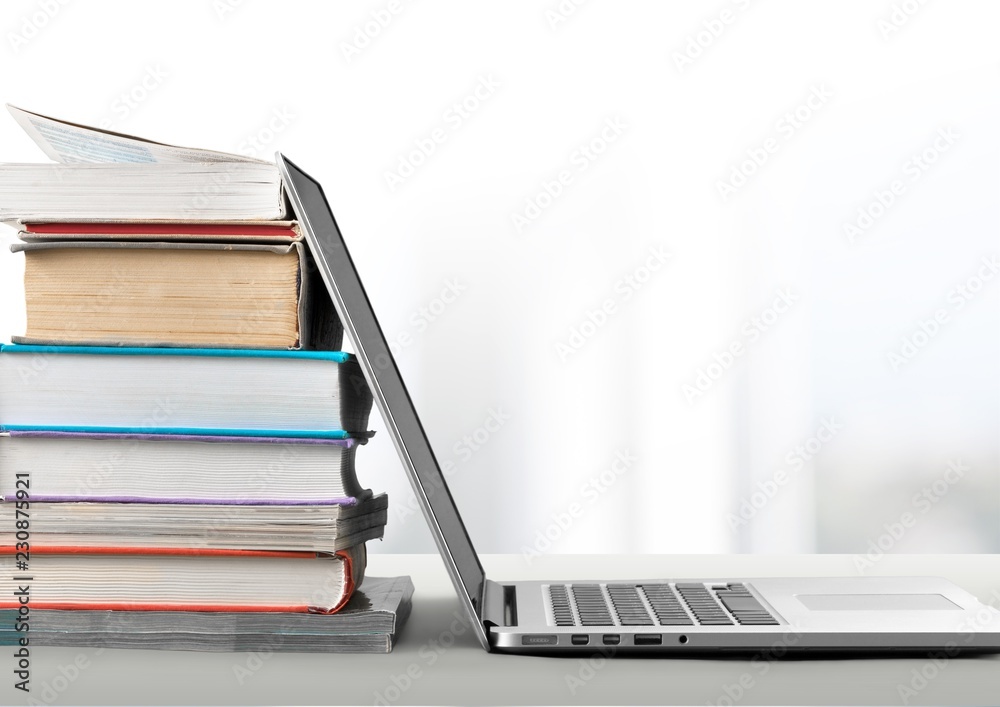 Stack of books with laptop on table