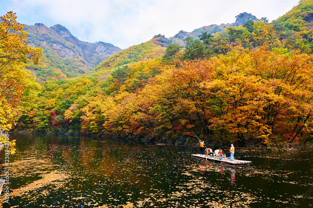 Sightseers on the bamboo raft in autumn lake.