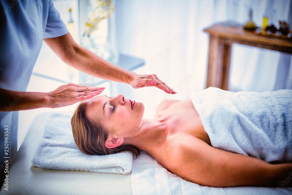 Therapist performing reiki on woman