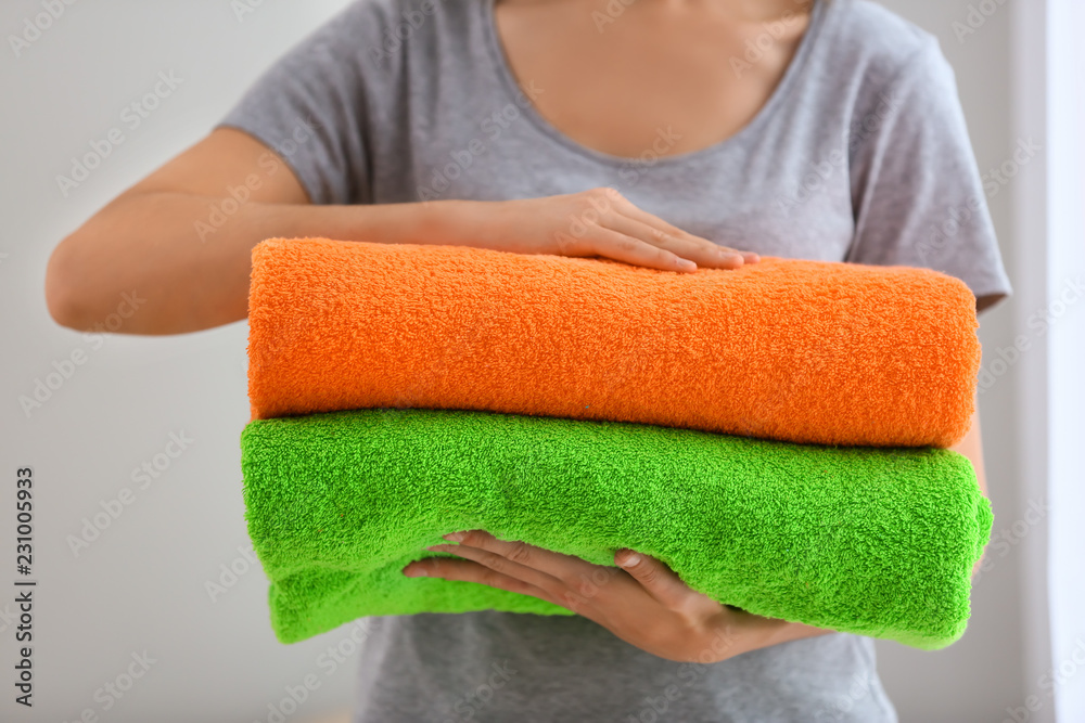 Woman holding folded color towels on light background