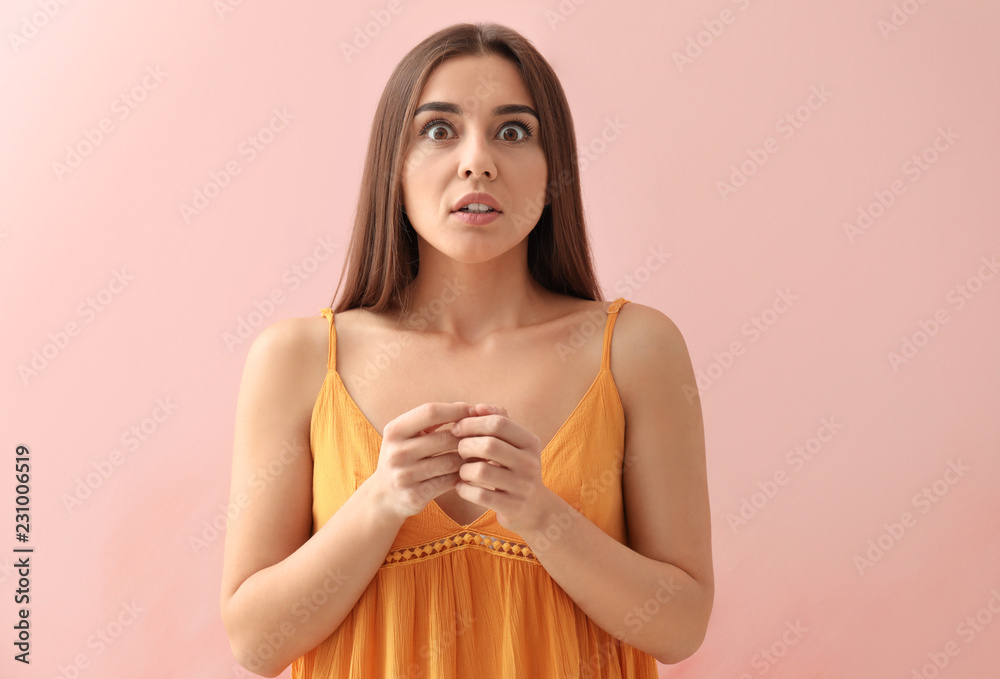 Shocked young woman on color background