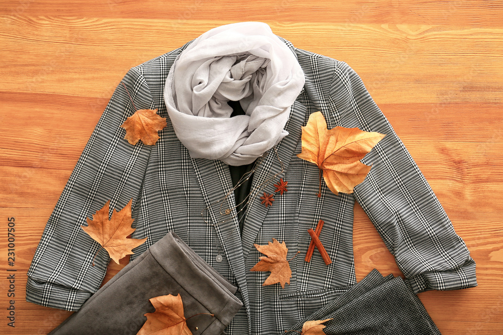 Stylish outfit with autumn leaves on wooden background, top view