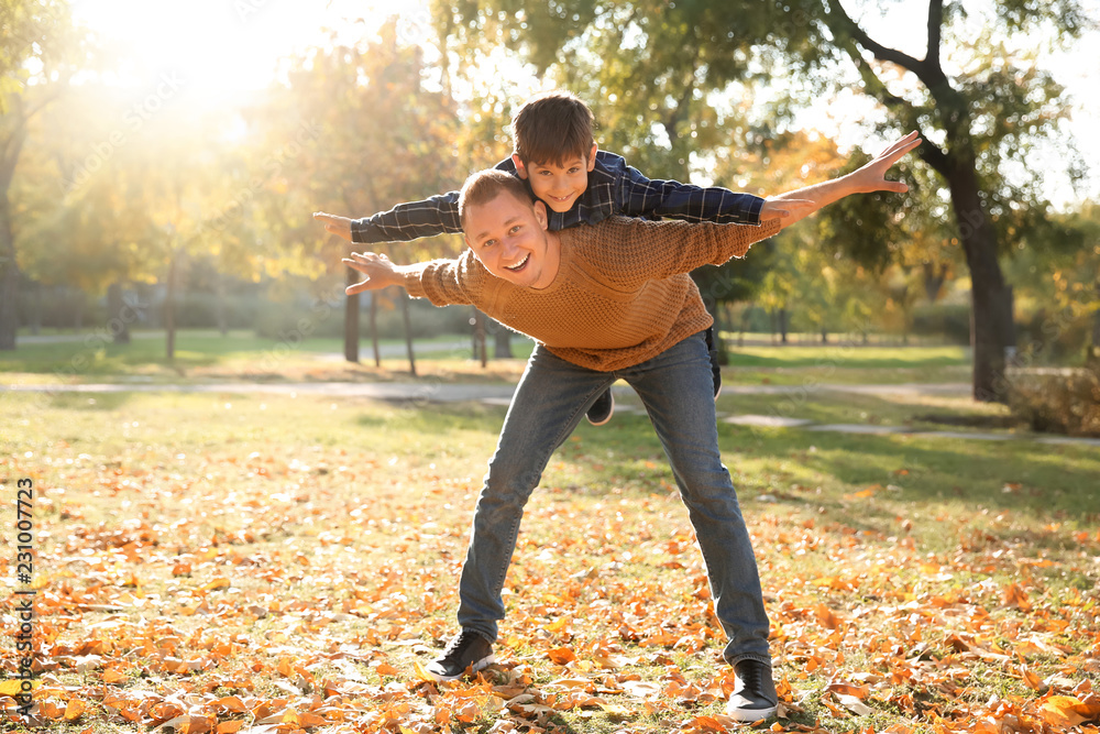 Happy father and son playing in autumn park