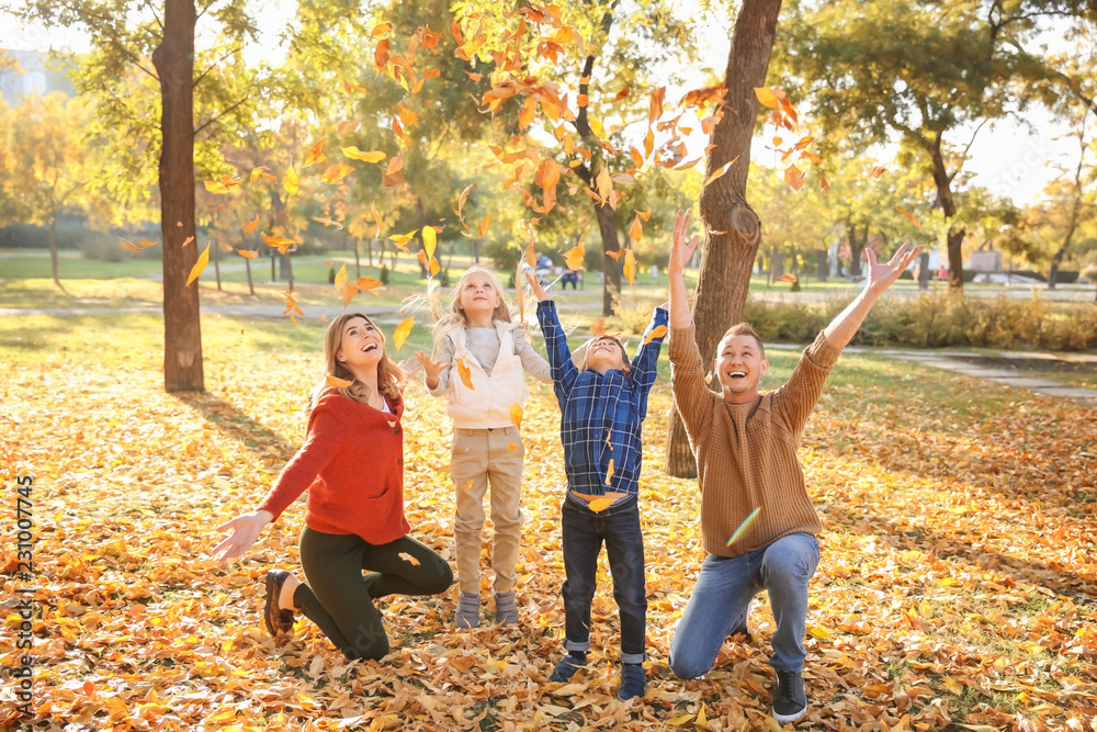 Happy family playing with leaves in autumn park