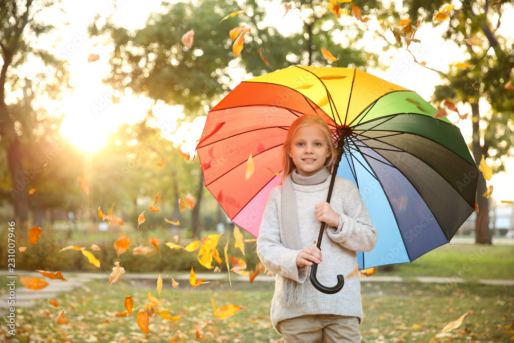 Cute little girl with colorful umbrella in autumn park