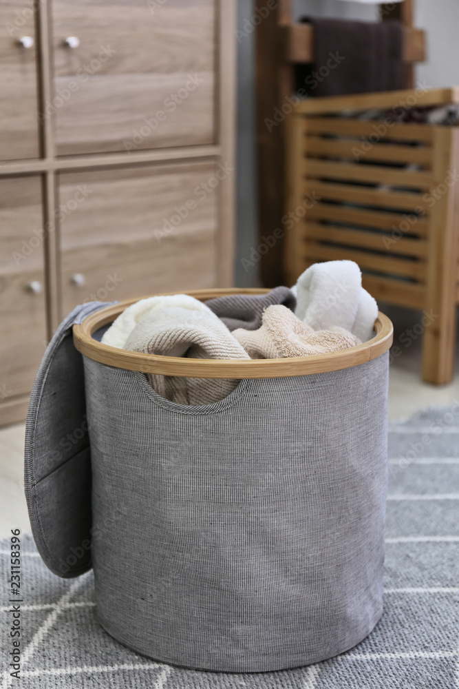 Laundry basket with dirty towels on floor in room