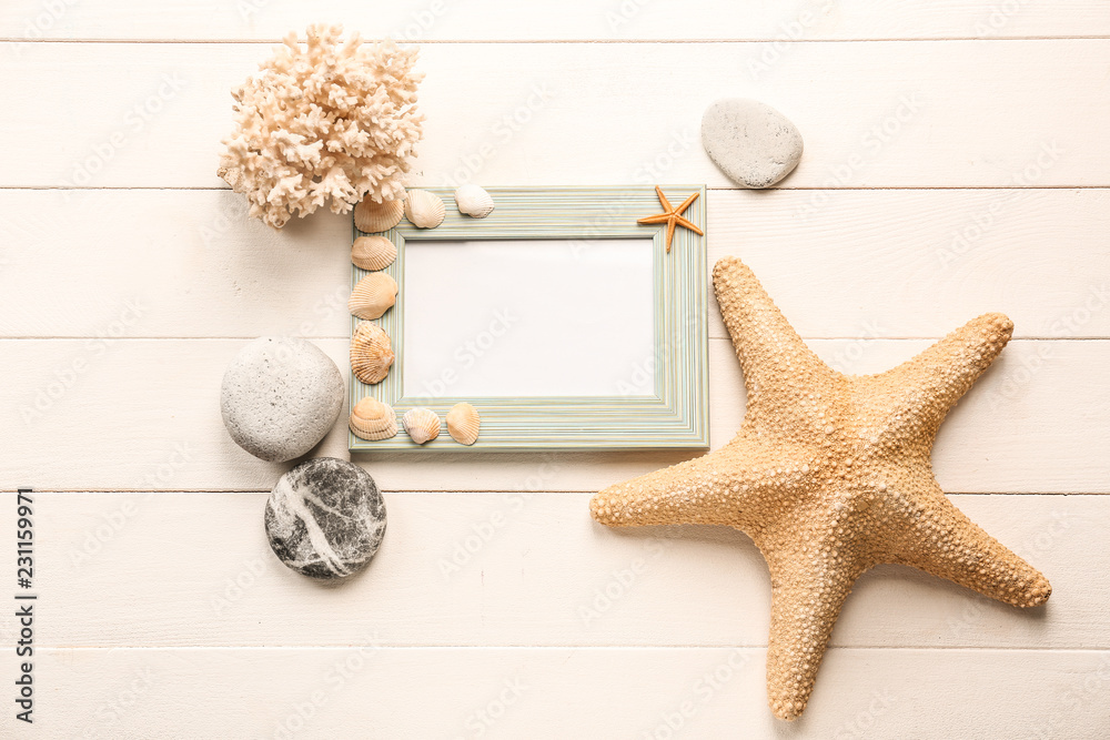 Empty frame with sea shells, starfishes and stones on white wooden background