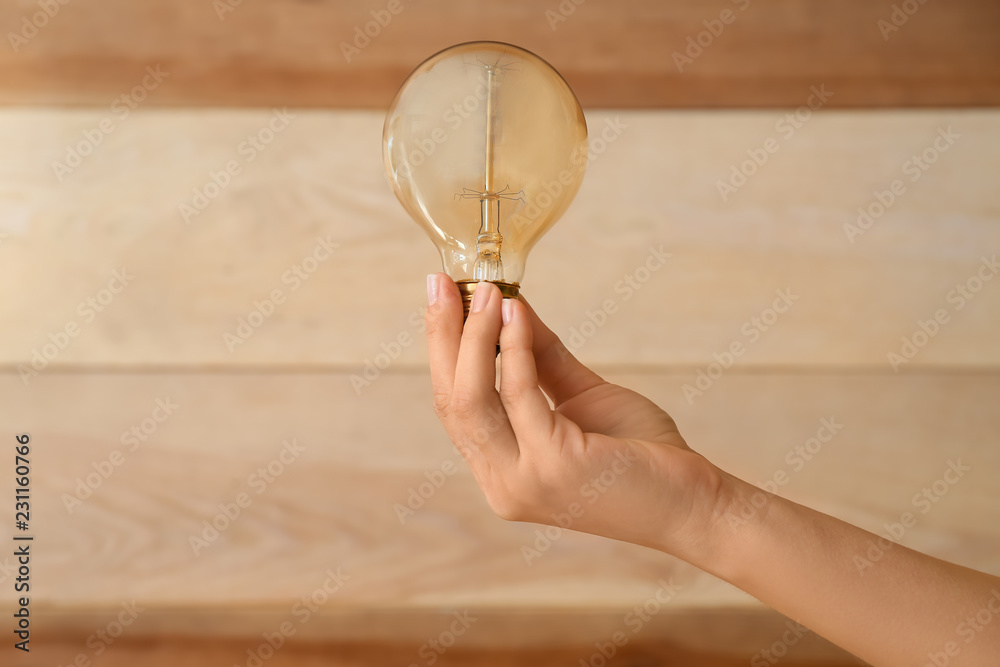 Female hand with eco light bulb on wooden background