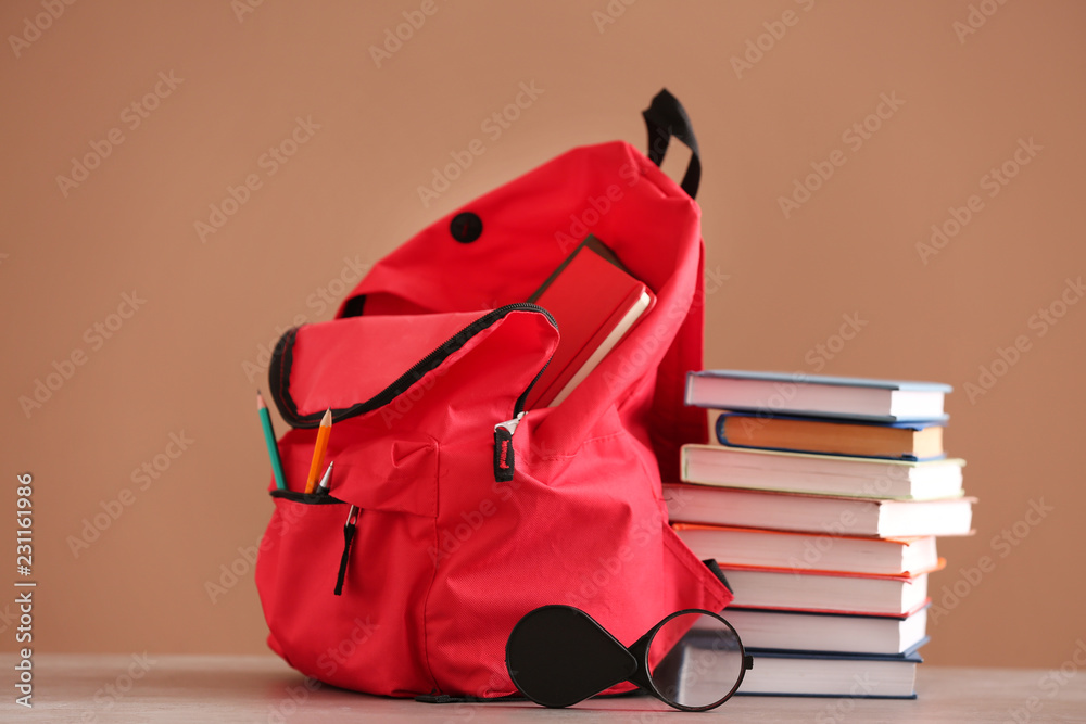 Backpack with school supplies on color background